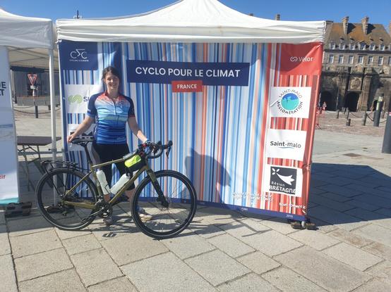 Moi derrière un vélo Gravel de location, devant un panneau cyclo pour le climat