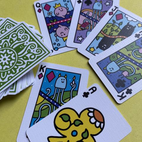 A photo of my a mini deck of cards. The fronts all have bright happy smiling creatures on them