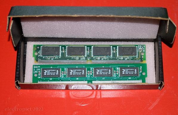 Sitting on a red biscuit tin, a small cardboard box padded with pink anti-static foam, containing two rather archaic computer memory modules.
