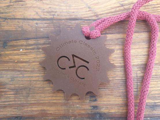 Médaille finish en plastique recyclé gravée avec un cycliste "climate Classic 2023, cycling 4 climate"
