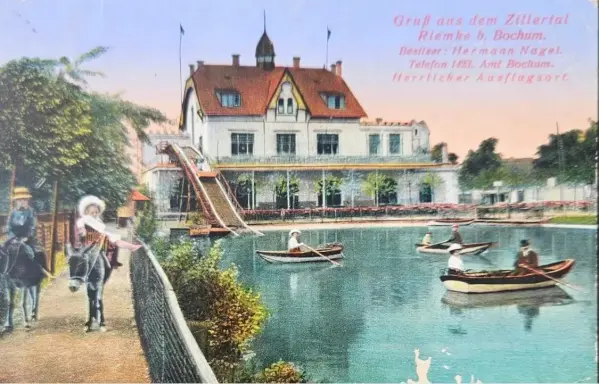 Postkarte eines Teiches mit Paddelbooten, einem Steg und einem großen Haus im Hintergrund