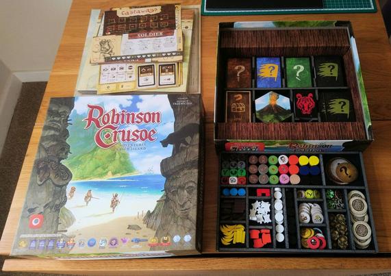 The box for the board game Robinson Crusoe: Adventures on the Cursed Island, opened up to show a custom insert used to organise the pieces into neat compartments.