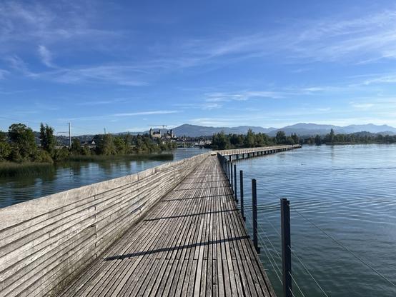 Wooden bridge across a lake, blue sky, sunny weather