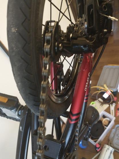 Bottom-up view of a bicycle chain passing through a derailleur, on a bike with tiny (12") wheels.