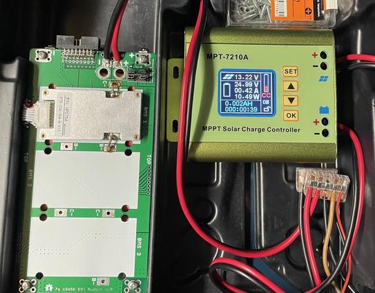 Closeup of a solar charge controller showing ~13V input voltage and ~24V battery voltage. Next to it a PCB hiding the battery pack