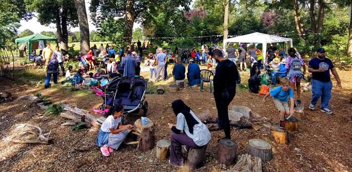 A crowd of people of all ages gathered at the Transition Ilford Forest Garden festival, chatting, exploring and enjoying the sunshine and workshops.