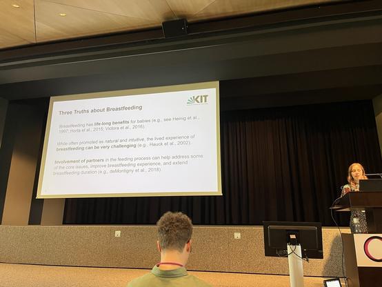 Screen with slide on the left, speaker on the right.

Slide reads

Three Truths about Breastfeeding

Breastfeeding has life-long benefits for babies (e.g., see Heinig et al.,
1997; Horta et al., 2015; Victora et al., 2016).

While often promoted as natural and intuitive, the lived experience of breastfeeding can be very challenging (e.g., Hauck et al., 2002).

Involvement of partners in the feeding process can help address some of the core issues, improve breastfeeding experience, and extend breastfeeding duration (e.g., deMontigny et al., 2018).