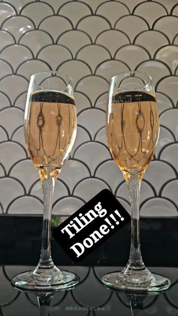 Two glasses of champagne with backdrop of white fish scale tiles