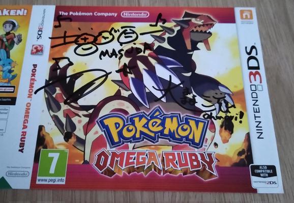 A signed sleeve of Pokémon Omega Ruby, featuring two autographs on the front from Junichi Masuda, and Shigeru Ohmori