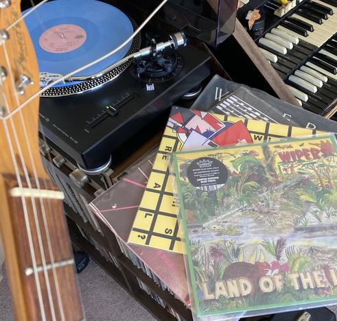 Guitar headstock, small amp and a pile of Wipers records, one blue record on the turntable. I’ve always learned songs by ear.