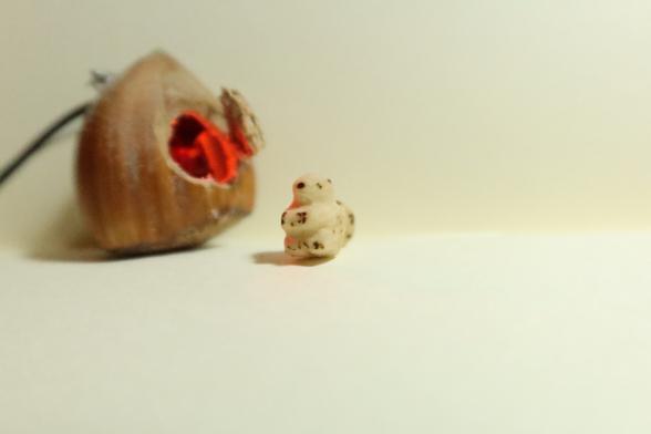 une petite sculpture d'écureuil devant une maison noisette