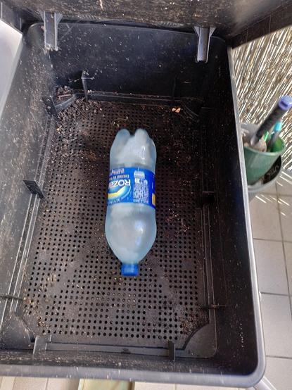 Dans un étage supérieur vide du lombricomposteur une bouteille d'eau congelée posée