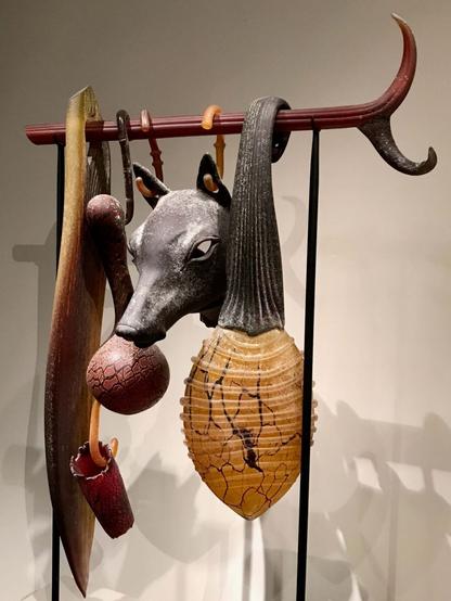 Photograph of the intriguing artwork 'Suspended Artifact: Jackal Mask with Baleen and Gourd' by William Morris, exhibited at the de Young Museum.