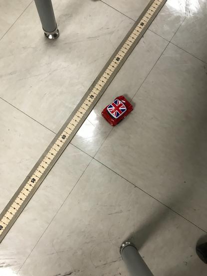 Data gathering in action!  This photo shows a pullback car next to a ruler.  The distanced travelled is being measured.  The pullback car is extra cute because it is a mini red cooper with the Union Jack on the  roof.