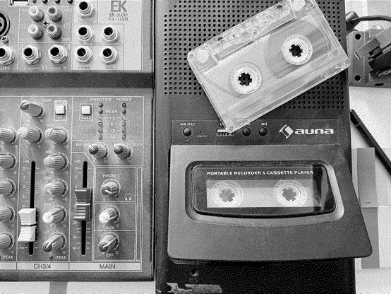 A sound table alongside a casette recorder. There are some post-its around and a pencil. The image is dithered in a grey scale