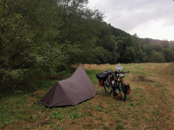 Ma tente et mon vélo au bivouac au bord d'une prairie