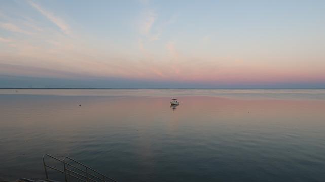 Sunrise over Cape Cod bay with a boat sitting quietly.
