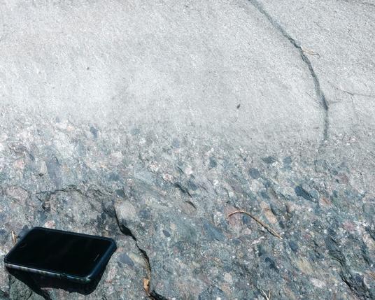 My photo of a pice of float, not attached to bedrock. I interpret depositional up is at the bottom of this photo, and it is reverse graded as a debris pulse flowed over fine-grained sediments deposited in quieter conditions. Cell phone for scale.