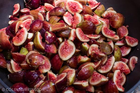 Photograph of a pot full of quartered figs with maroon skin, white flesh, and ruby centers.