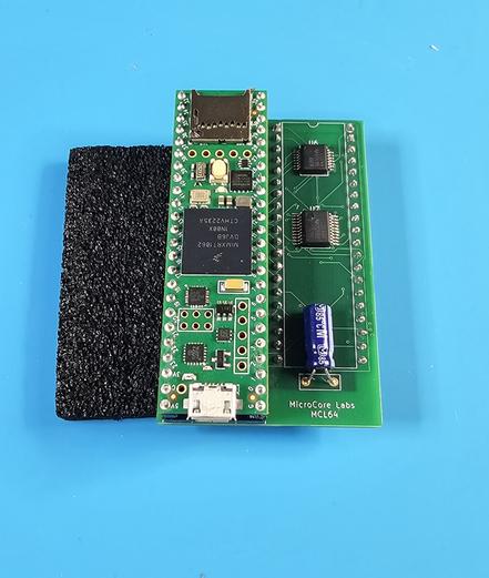 A green adapter board pcb with small logic chips and an Arduino Teensy sitting on top.