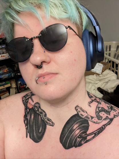 Selfie, sunglasses, tattoo on collar bone of snakes wrapped headphones