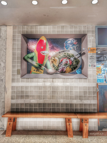 Frey tile wall with 3D decoration of weird creature with spoon and big bowl of salad