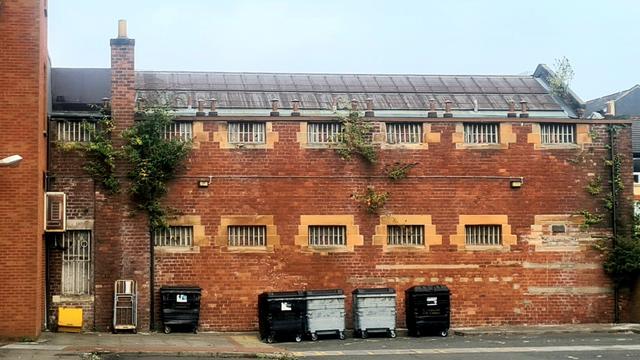 A two storey brick-built building wtih small windows set high above the ground. These windows are barred with iron bars.