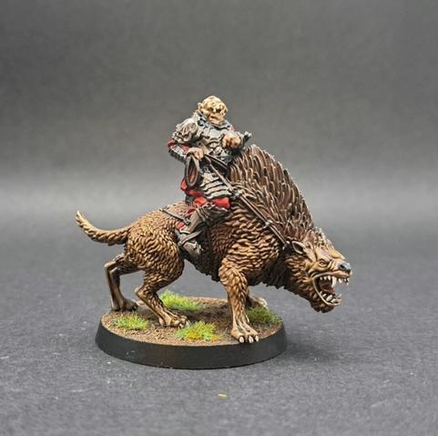 Gothmog on a Warg. Gothmog has pale skin and wears heavy armour with red fabric showing. The warg is brown, with the fur being darker at the top. And lighter down by his feet. The teeth and tongue are visible as the warg has its mouth open