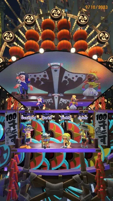 Four squid/octo teammates stand on a float underneath the Splatoon 3 idols Shiver, Frye, and Big Man, whom are dancing and singing.