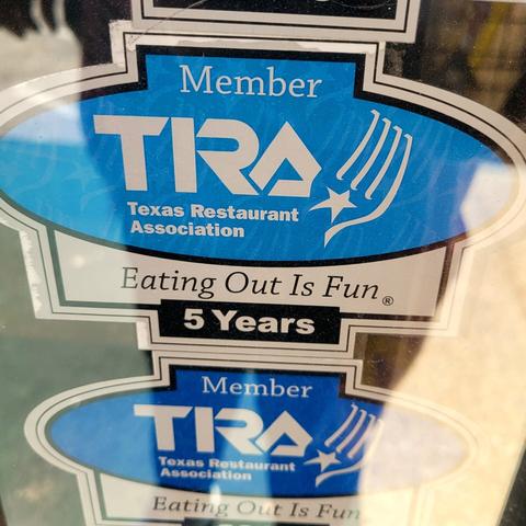 A Texas Restaurant Association (TRA) Member sticker on a window who's slogan states: 'Eating out is fun.'