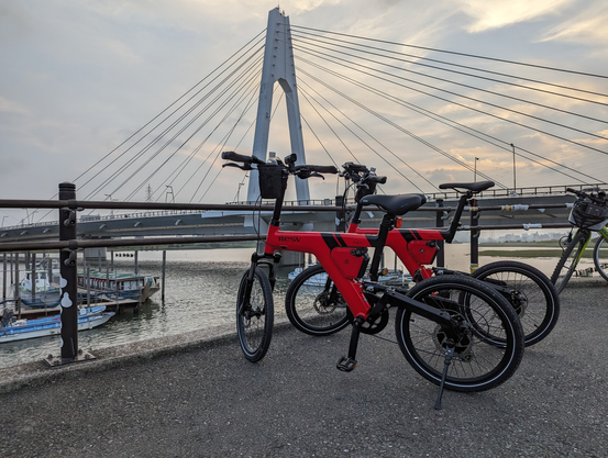 Two red BESV PSA1 bicycles with a bridge and boats in the background