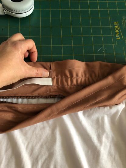 The inside of a waistband with channels stitched and an elastic partially inserted