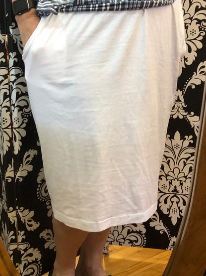 A white straight skirt with side seam pockets in front of a paisley black and white divider