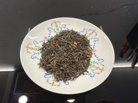 Darjeeling Tindharia tea on a white naval-decorated porcelain saucer.