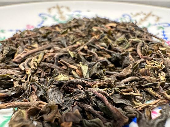 Macro look on the Darjeeling Tindharia tea on a white naval-decorated porcelain saucer.