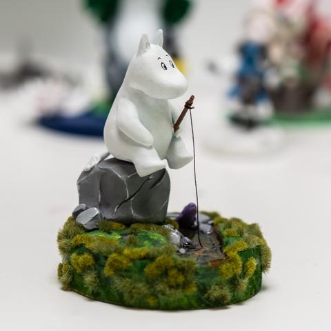A moomin sitting on a rock, fishing in a small stream, Clayfigure, about 12cm high on a woodenbase. Details see post.