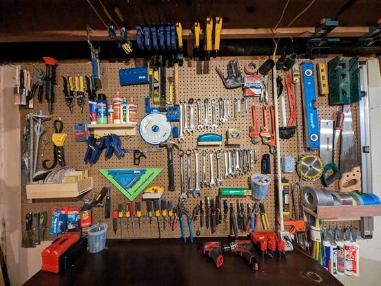 A workbench with a peg board filled with tools