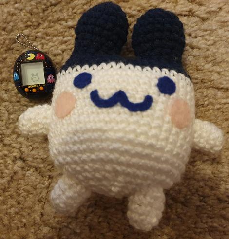 Crochet plush of Mimitchi, next to a Pac-Man Tamagotchi with Mimitchi on it