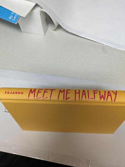 A yellow book with red type, titled Meet Me Halfway.
