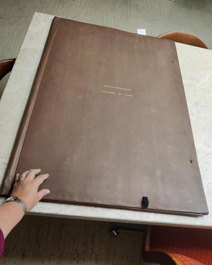 Tiny hand showing scale of very large brown portfolio holding the broadsides