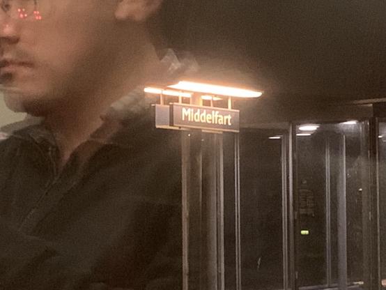 Picture of the middlefart sign through the window with a reflection of a fellow passenger