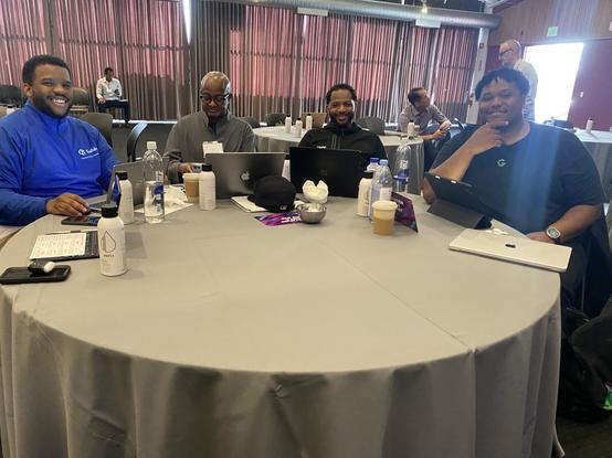 Four black men, all CEO’s and founders of startups sit smiling at a round table.