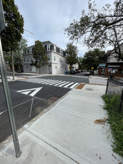 A raised four way intersection with pedestrian crosswalks in front of a house and corner store