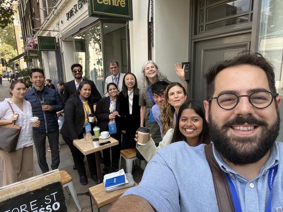 Larger group of people outside a cafe smiling for a selfie