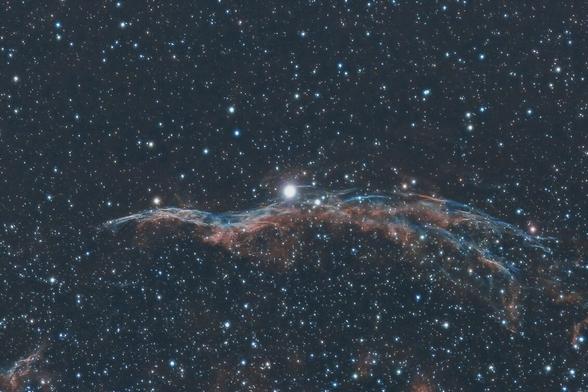 Wispy blue and red nebula forms the Western Veil Nebula.