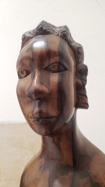 Head of sculpture in dark grained wood of an African woman. She is gazing steadfastly left.