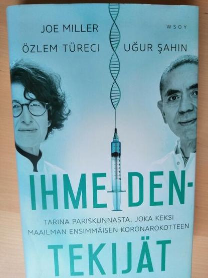 Ihmeidentekijät-kirjan kansikuvassa Biontechin perustanut turkkilaistaustainen tutkijapariskunta. Keskellä "rokoteruisku", josta lähtee RNA:n tai DNA:n näköisiä kierrekuvioita.