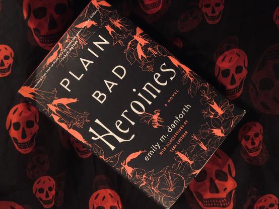 Pictured is PlainBadHeroines (with cover art of red on black) on a background of black with red skulls. Photo by AHS.