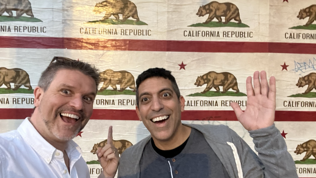 Aaron Quigley and David Ayman Shamma pointing and waving in front of ￼a wall of multiple Californian state flags