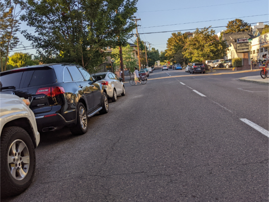 Parked cars blocking visibility of cross street traffic on a two-lane one-way that induces speeding car traffic.